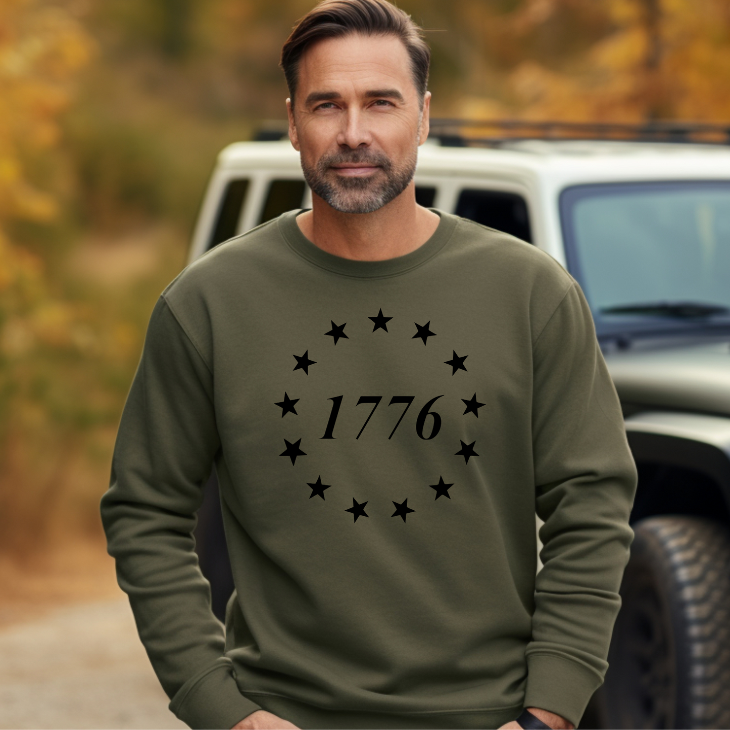 1776 design with 13 stars on military green crewneck sweatshirt, modeled outdoors near vehicle.