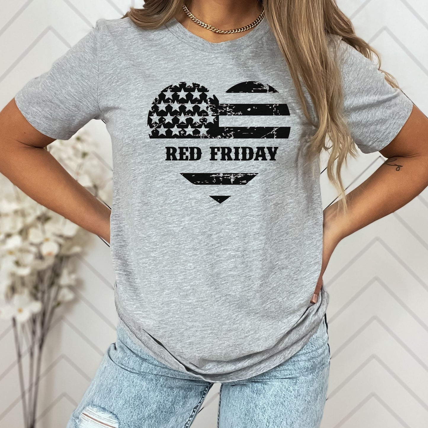 Distressed Red Friday heart flag design on athletic grey women's t-shirt, modeled with light-wash jeans.
