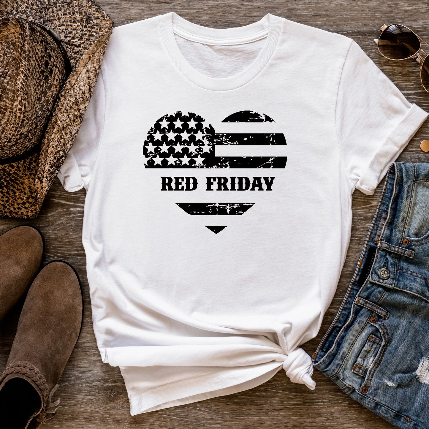 Red Friday distressed heart flag design on white cotton t-shirt, flat lay styled with jeans and hat.