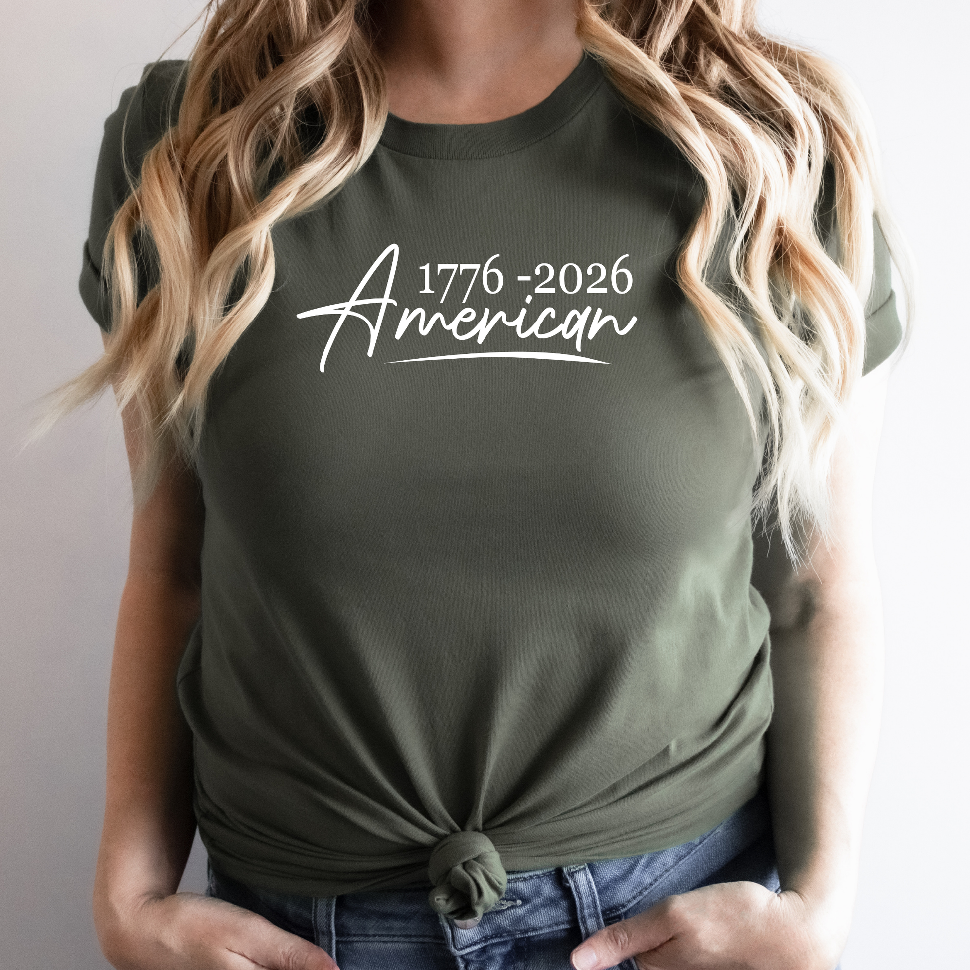 Person wearing a green t-shirt with '1776-2026 American' text.
