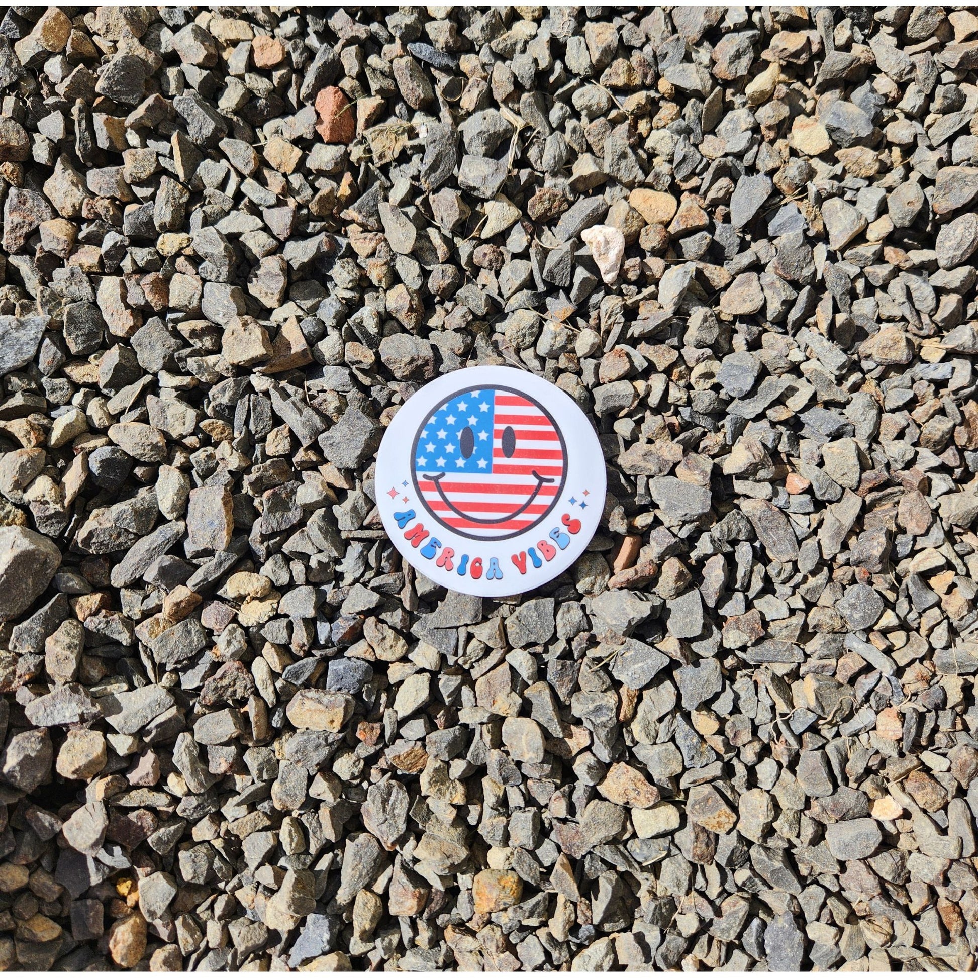 America Vibes smiley face sticker with American flag design on rock background.