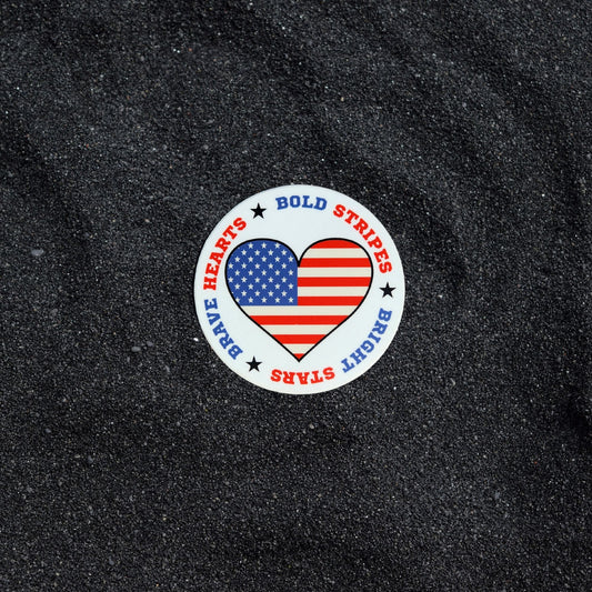 Bold Stripes, Bright Stars, Brave Hearts patriotic heart sticker on black sand background.