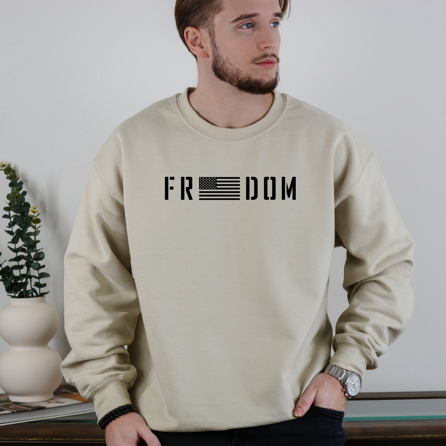 Freedom flag graphic on sand unisex crewneck sweatshirt, modeled indoors.