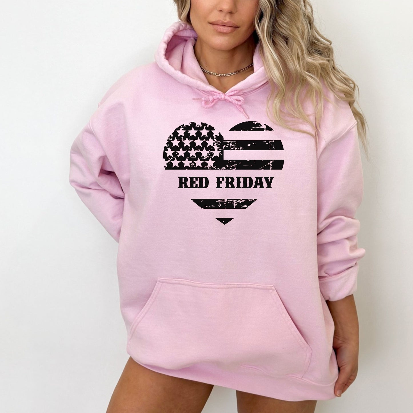 Red Friday heart-shaped flag graphic on pink women's hoodie, modeled against white backdrop.