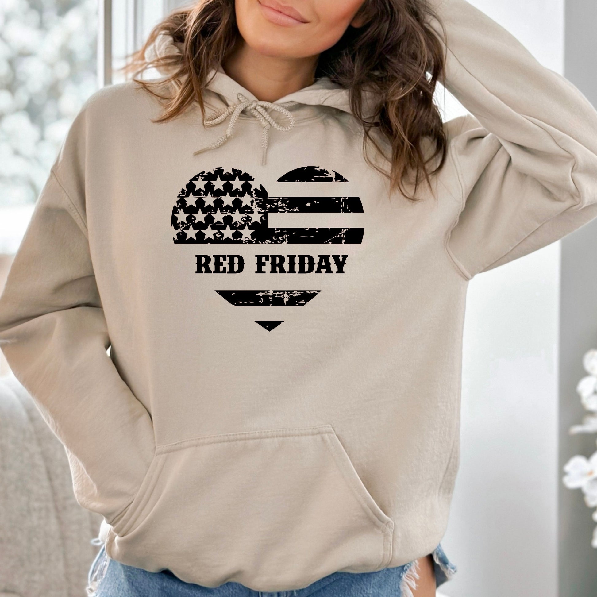 Red Friday distressed heart flag on soft sand women's hoodie, modeled indoors with cozy background.