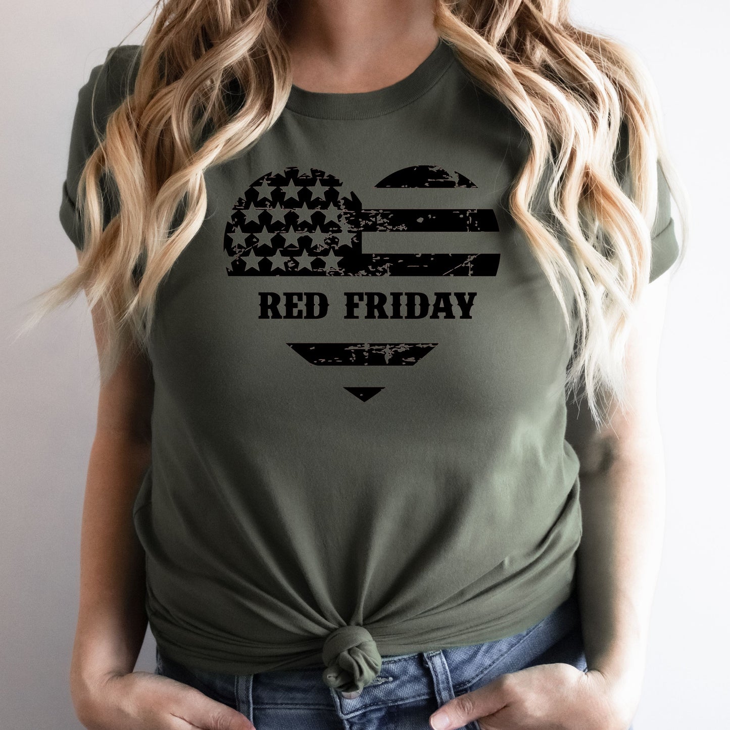 Red Friday heart-shaped flag graphic on military green women's t-shirt, modeled indoors with natural light.