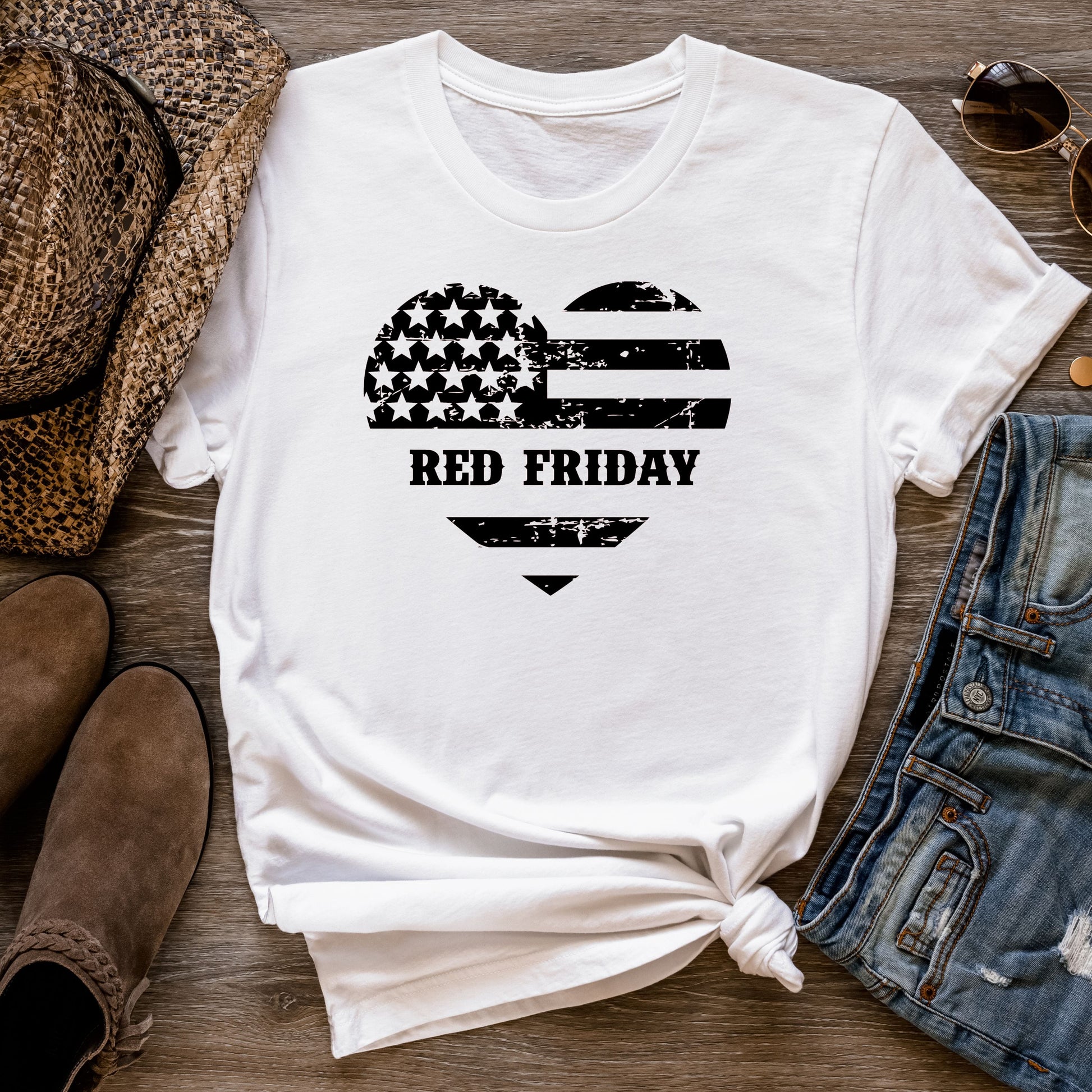 Red Friday distressed heart flag design on white cotton t-shirt, flat lay styled with jeans and hat.