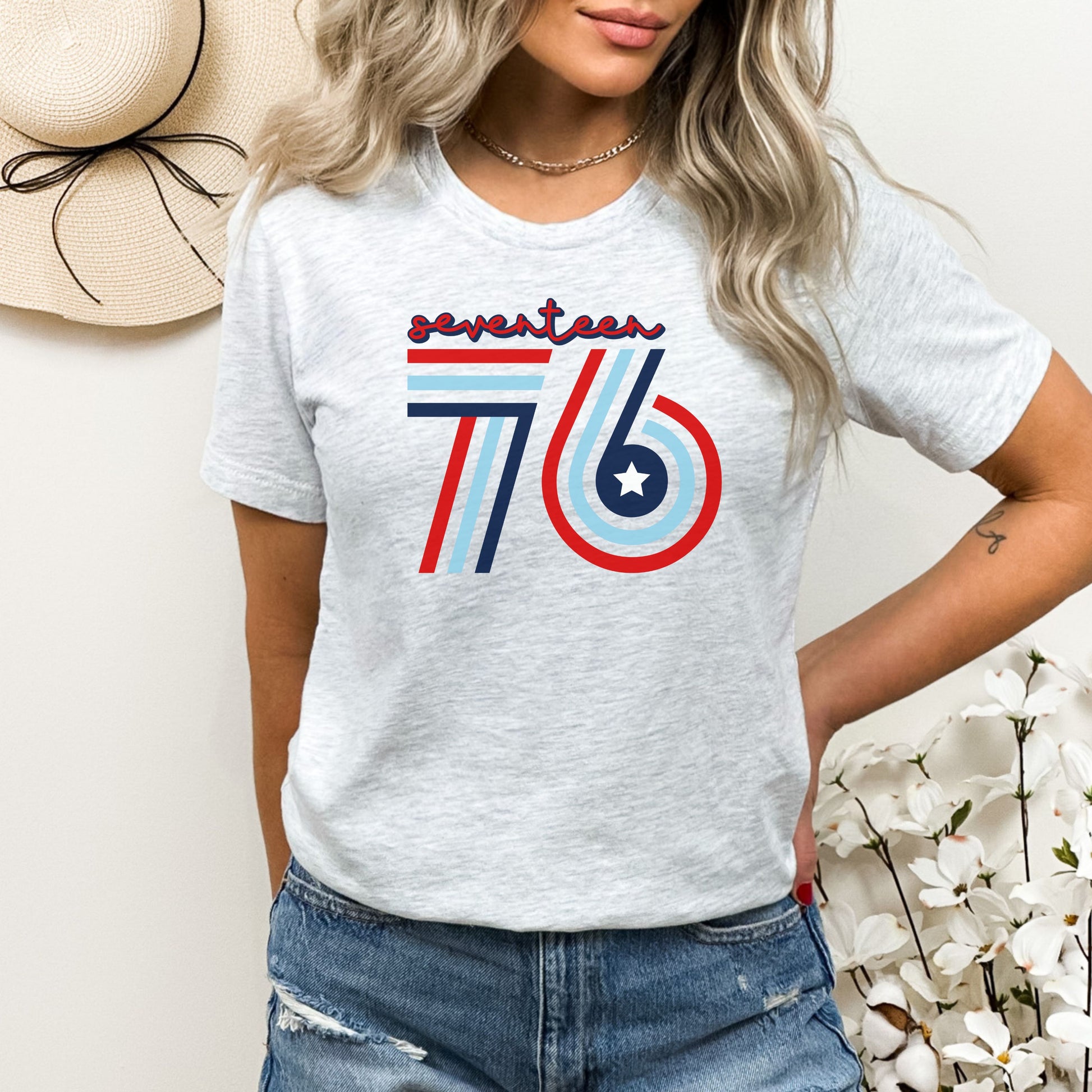 Seventeen 76 vintage type in patriotic colors on ash grey women's t-shirt, modeled with floral decor.