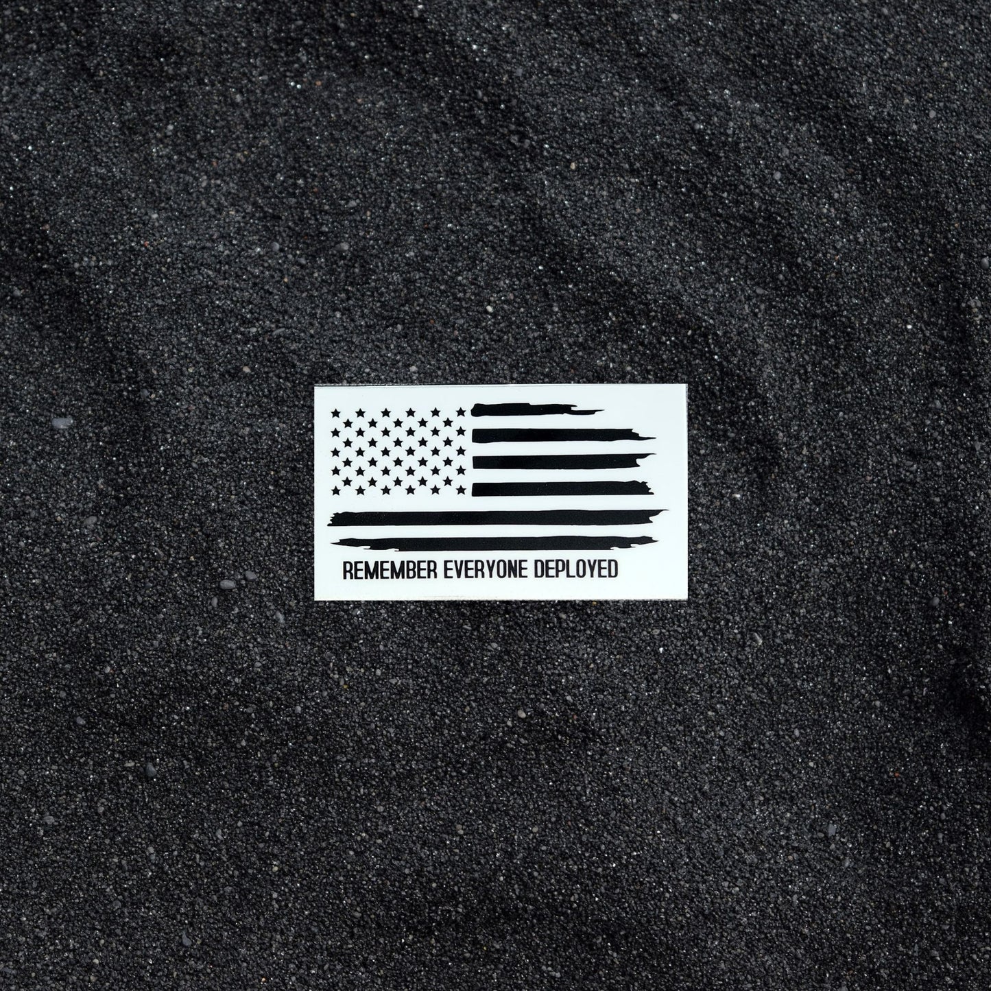 Remember Everyone Deployed sticker on black sand background.