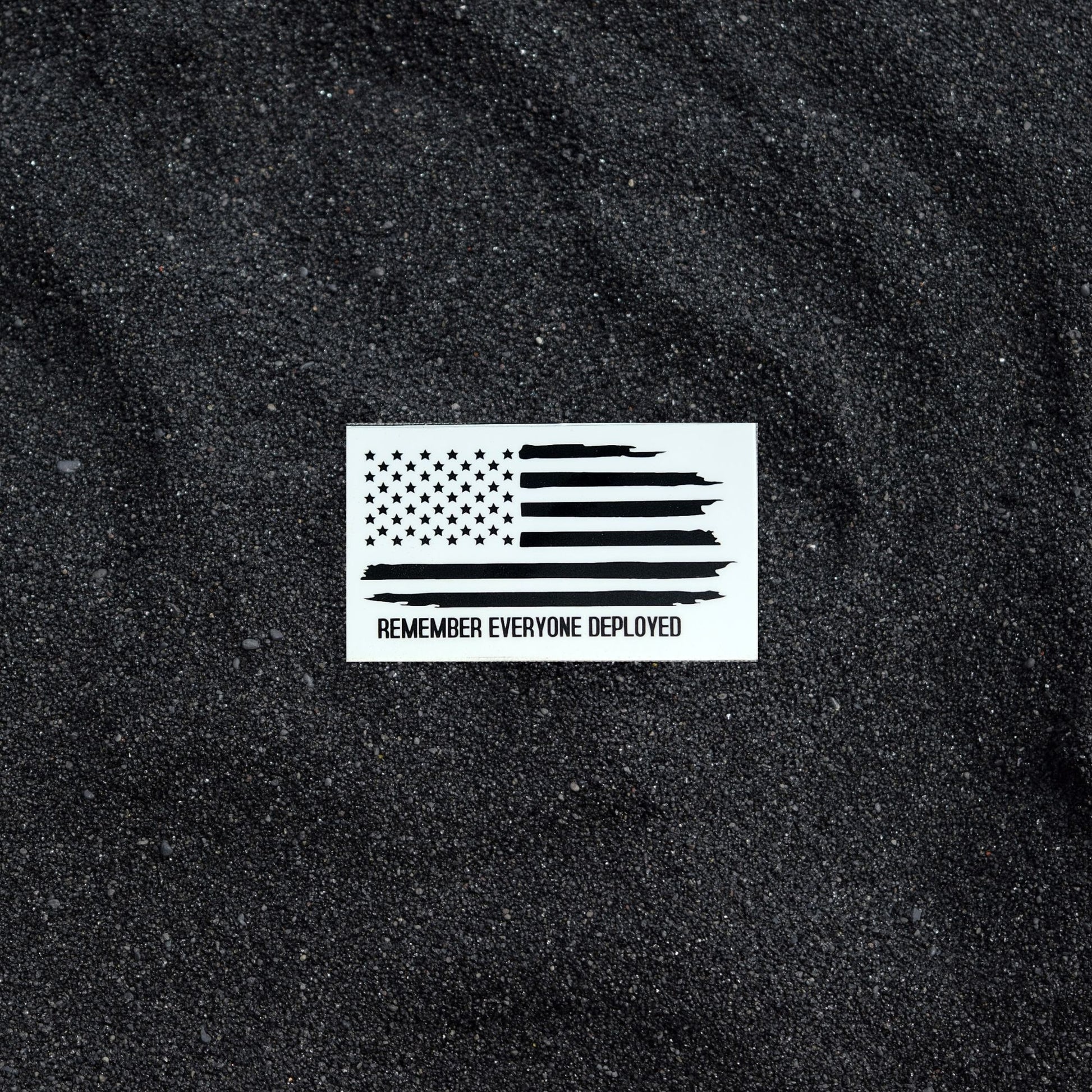 Remember Everyone Deployed sticker on black sand background.