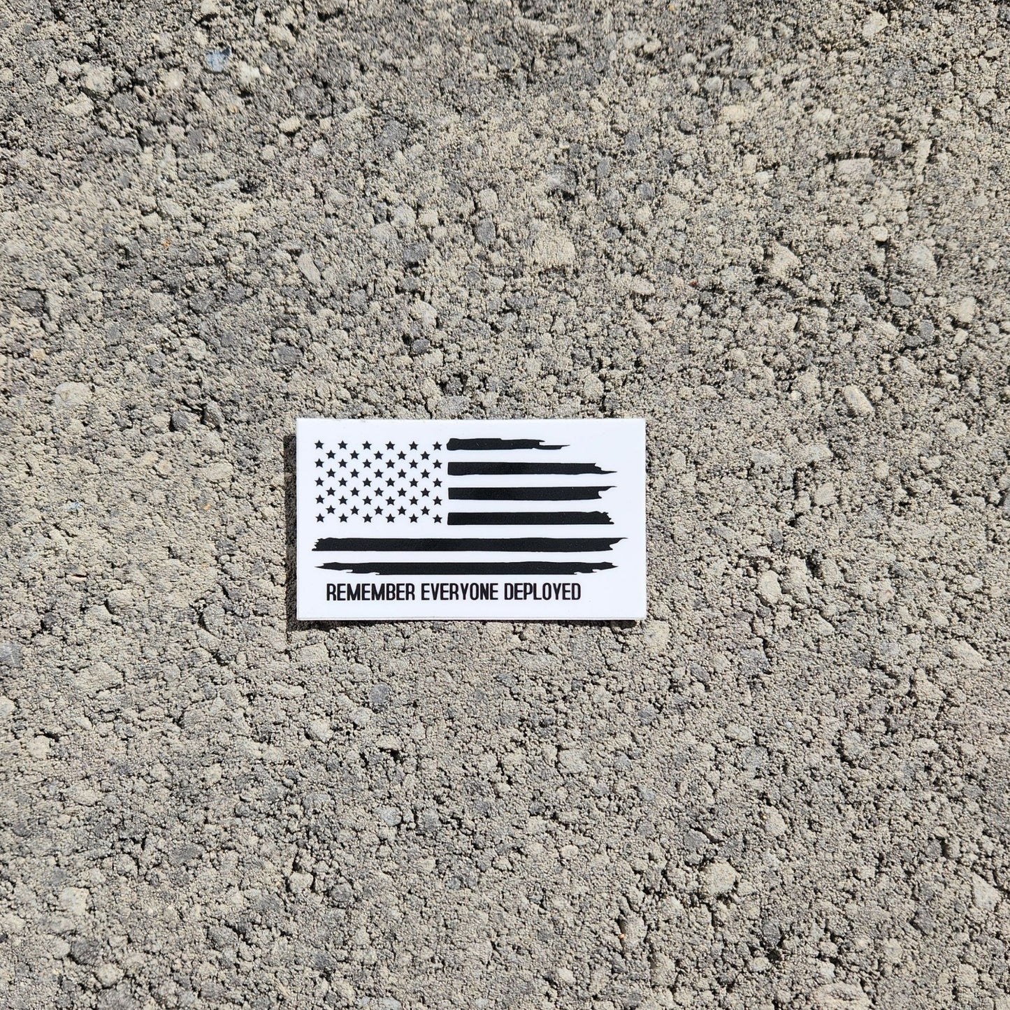 Rectangular R.E.D. sticker on concrete background showing distressed flag.