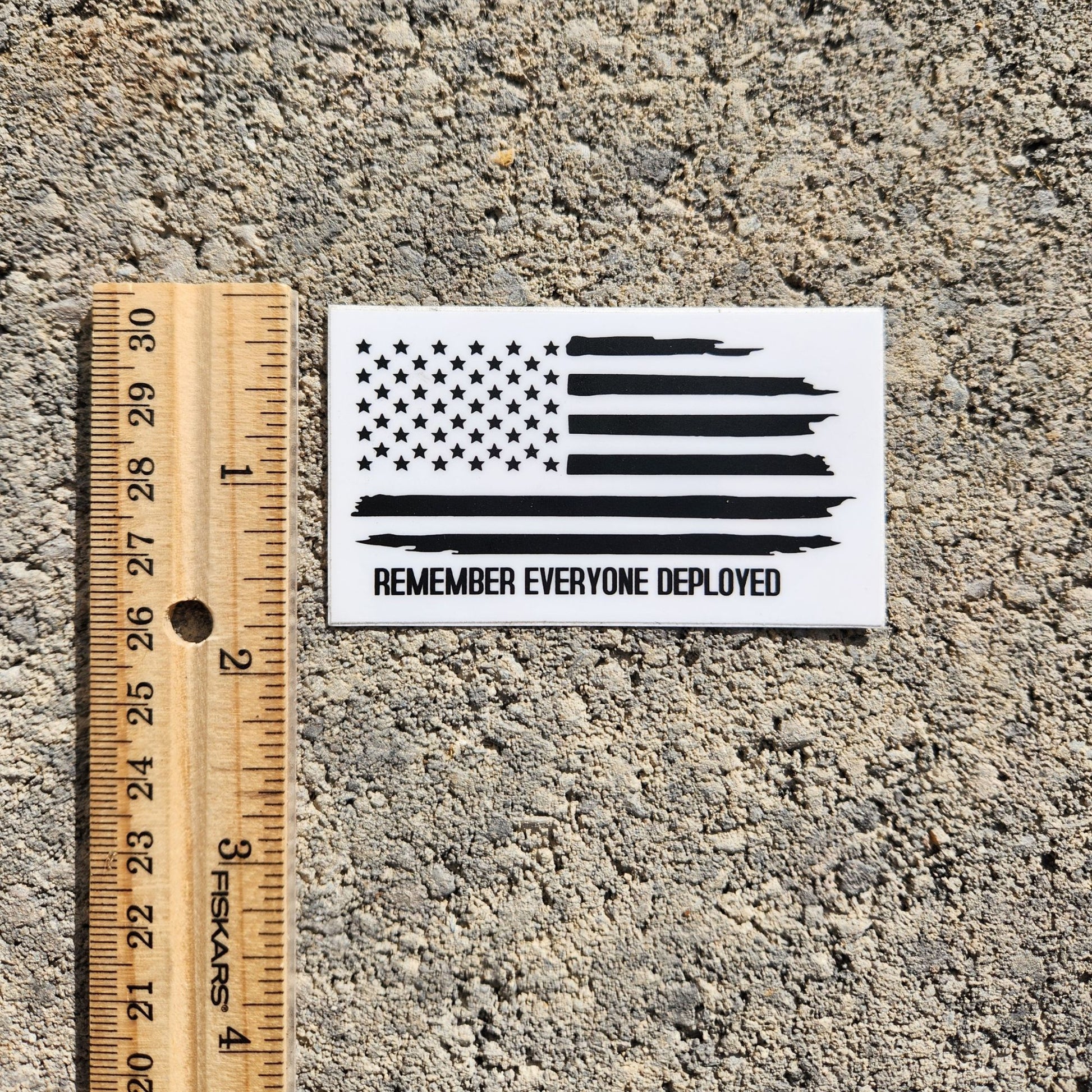 Size comparison of Remember Everyone Deployed flag sticker with ruler.
