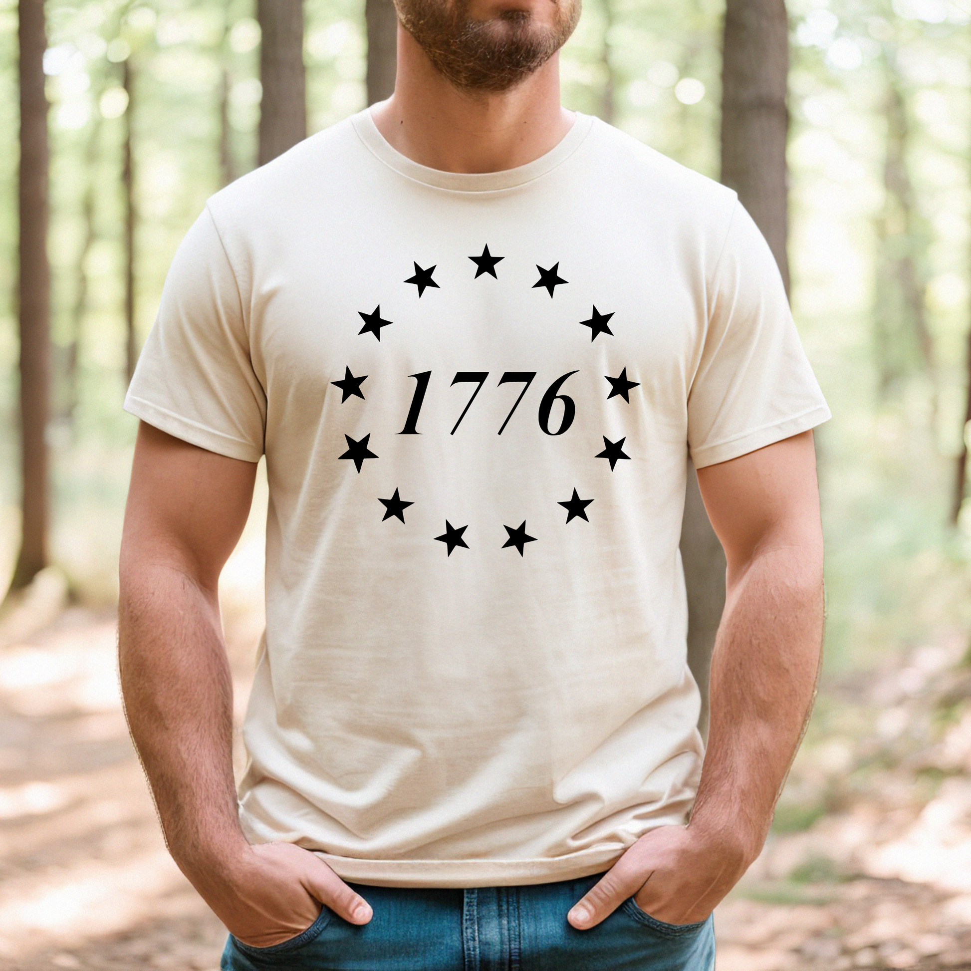 Natural colored t-shirt with black 1776 circle star design, worn in an outdoor forest setting.